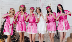 Eine Gruppe Mädels in pinken Bademänteln vor einer weißen Wand posiert für ein JGA-Foto